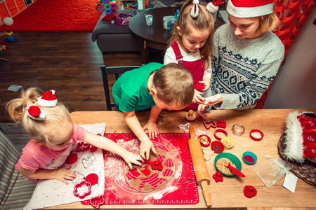 烤圣诞饼干。 圣诞姜饼饼干有许多形状，装饰着五颜六色的霜，洒上糖霜巧克力涂层，放在桌子上。 烤传统饼干。 一家人庆祝圣诞节。 在