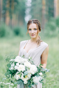 闺房照片拍摄新娘在树林里用花束。 公园里的飞行服和美丽的女孩。