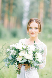 新娘穿着婚纱在大自然中带着一束花。 闺房照片拍摄在松莱木的艺术风格。