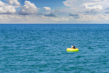 一个年轻的女人在一个游泳圈里漂浮在海面上。 一个女孩正在充气戒指上的海面上放松