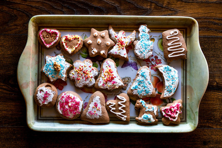 圣诞姜饼饼干，多种形状，装饰着五颜六色的霜，洒上糖霜，巧克力涂层，放在托盘上。