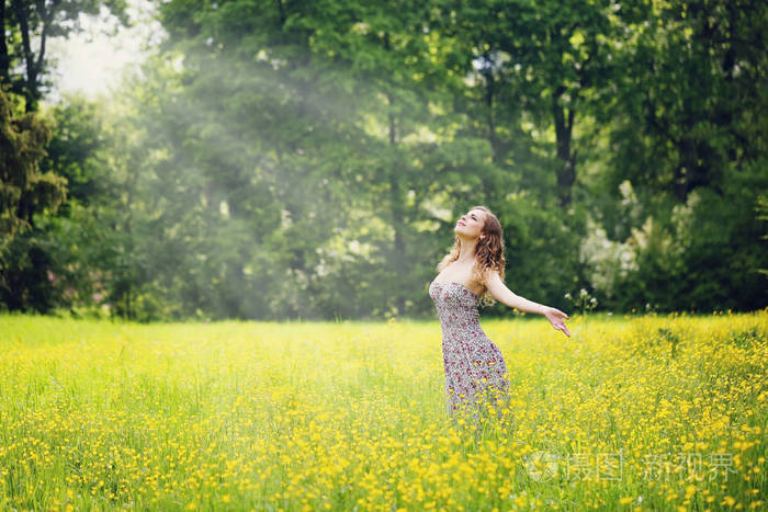 在草地上享受大自然的女人。 张开双臂，清晨清新的空气，夏天的田野在日出时。