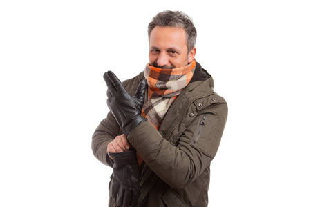 穿着冬季夹克和橙色围巾的男人戴上手套,准备迎接寒冷的天气,隔离在
