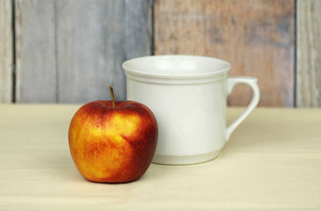 一杯白茶和一个苹果放在桌子上作为早餐
