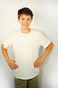 穿短裤和白色T恤的男孩站着微笑。他的眼睛很漂亮，牙齿也很健康。白色背景