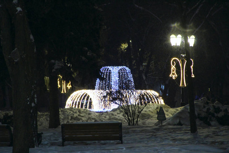 黑暗中花环上明亮的灯笼和喷泉。 新年的假日花环。 夜街的圣诞灯。 城市公园的灯笼照明