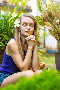 有热带植物的年轻女子在花园里冥想