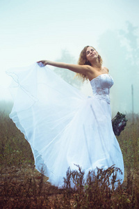一位美丽的新娘，她的背景是一片雾蒙蒙的田野