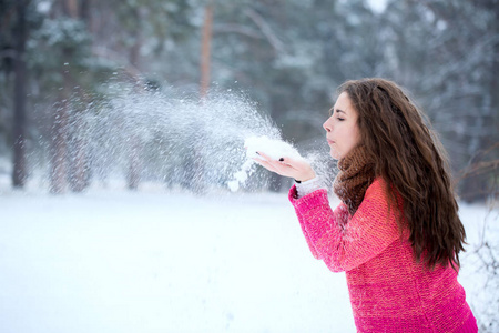 年轻漂亮的女人手中吹着雪