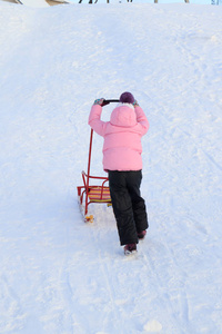 冬天，一个女孩在雪地里玩雪橇