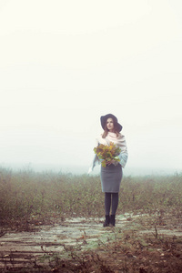 一个戴帽子的漂亮女孩走在秋天的田野上