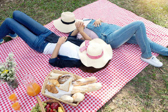 女朋友躺在帐篷前的野餐布上,概念是爱情朋友还是同性恋