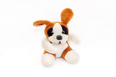 柔软的白色和棕色玩具狗。 坐在白色的背景上。 孤立的