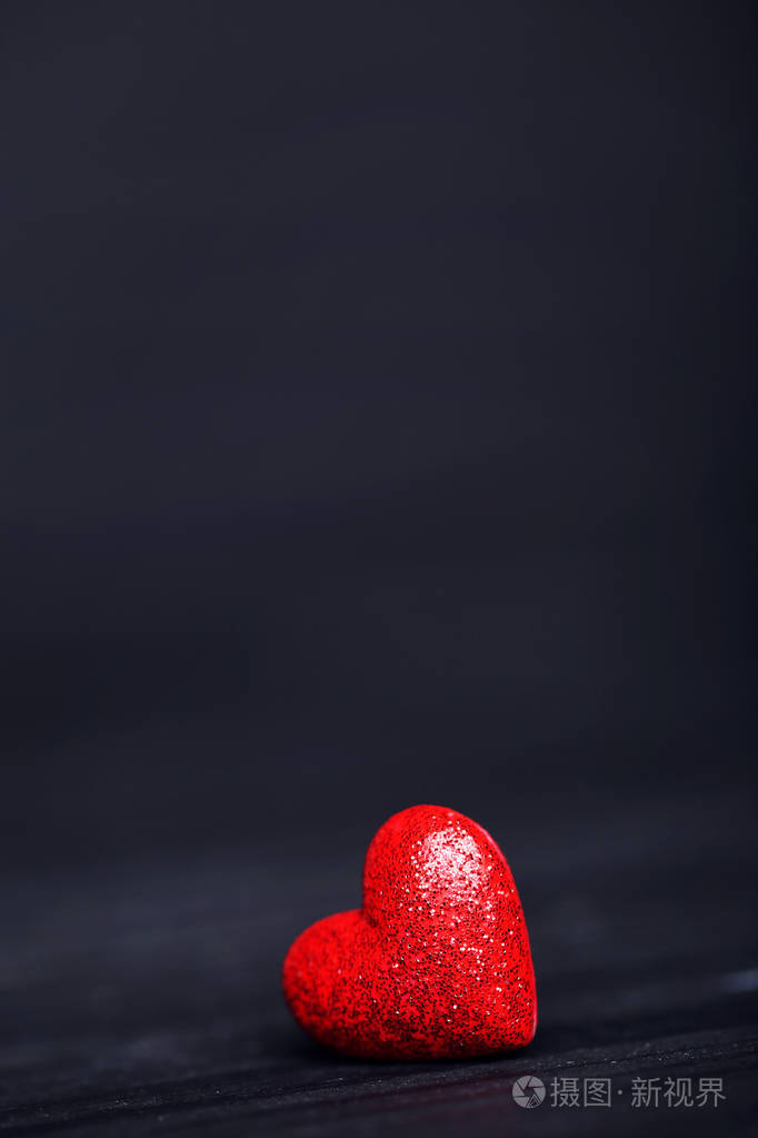 黑色的木桌上放着红色闪光的心