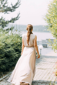 闺房照片拍摄新娘在公园与花束。 一件飞裙和一个美丽的女孩在湖边。