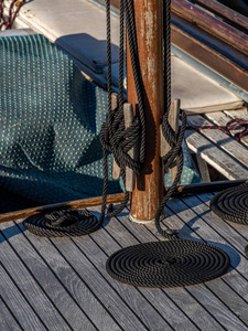 木船甲板上成圈排列的绳子的肖像图。 绑在桅杆上的绳子。