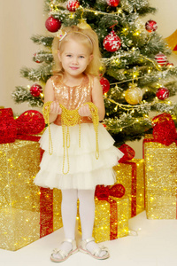 圣诞树附近的小女孩拿着装饰品