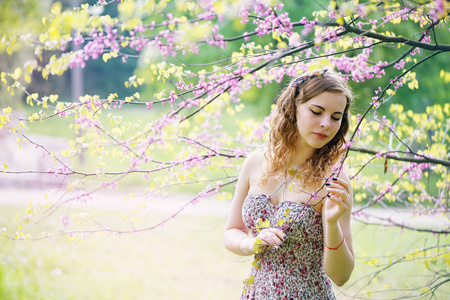 一个美丽的女人在春天的花园里，在一棵盛开的树下