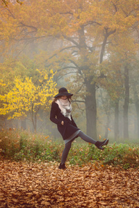 一个穿着外套戴着帽子的漂亮女孩走在秋天的森林里