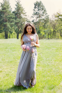 一位美丽的孕妇，在一片长满玉兰枝的草地上