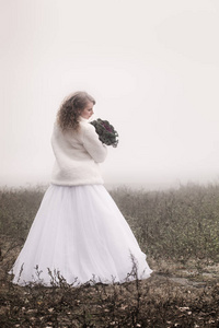 一位美丽的新娘，她的背景是一片雾蒙蒙的田野