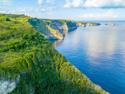 印度尼西亚。 佩尼达岛的海岸。 岩石上的丛林。 蓝天上的云。 空中景色