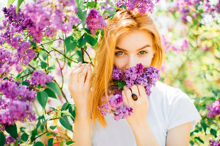 公园里一个年轻迷人的女人，带着盛开的丁香花