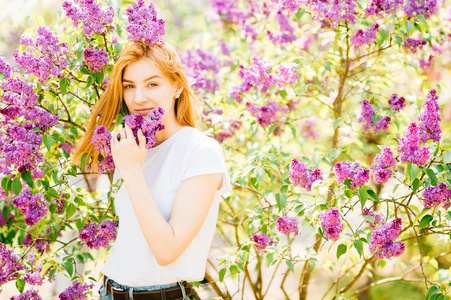 公园里一个年轻迷人的女人，带着盛开的丁香花