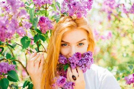 公园里一个年轻迷人的女人，带着盛开的丁香花