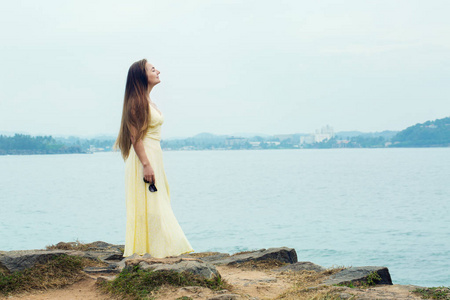 美丽的长发女人，穿着一件长裙子在海滩上