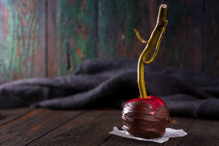 一个红苹果在黑色巧克力涂层与棍子。 万圣节甜点