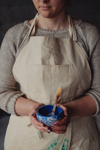 在陶瓷工作室里，一位身着米色围裙的女工，手牵手制作的陶瓷陶器设计师，画碗