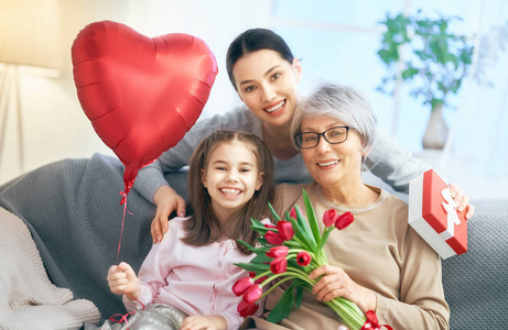 s day Child daughter is congratulating mom and granny giving th