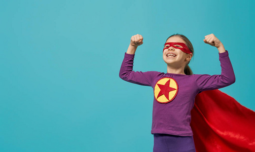 小孩子在扮演超级英雄。 亮蓝墙背景上的孩子。 女孩权力概念。