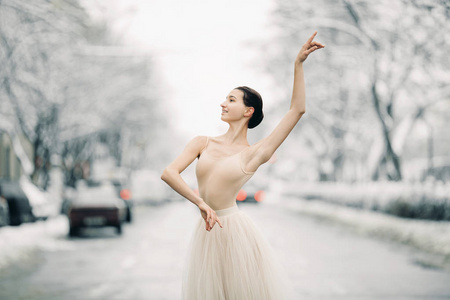 美丽的芭蕾舞女演员穿着透明的裙子,在雪城的街道上汽车里跳舞.