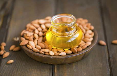 护肤和脱发成分.杏仁油和杏核木质背景.杏仁油放在一个小罐子里.