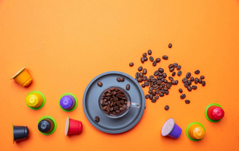 咖啡杯豆子和胶囊豆荚在明亮的橙色背景复制空间顶部视图