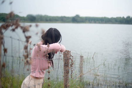 一个年轻的女人绝望地靠在篱笆上。