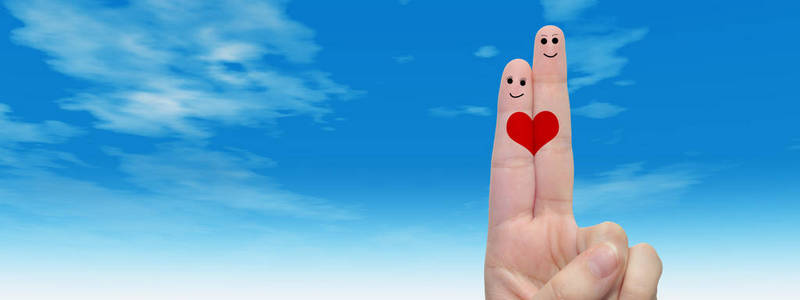概念或概念人类或女性的双手，用两个手指画着红色的心和微笑的脸在云蓝色的天空背景横幅上