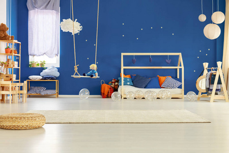 带有金色星星的蓝色墙壁，别致的斯堪的纳维亚儿童房，配有带枕头的木床和玩具
