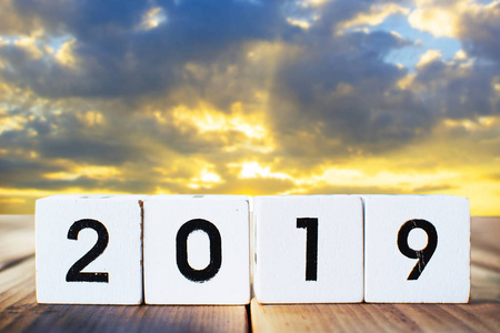 2019字在木盒上的一块木板和天空日落背景概念新年快乐。
