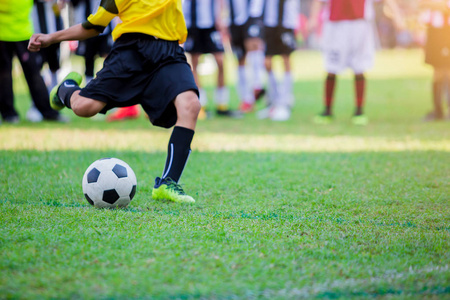 儿童足球运动员跑着在绿草上射门。 足球比赛足球运动员训练