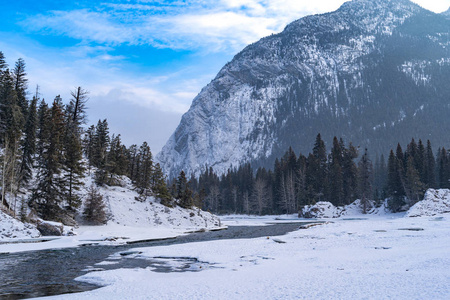 班夫国家公园弓河的冬季场景，有开阔的河流冰雪。