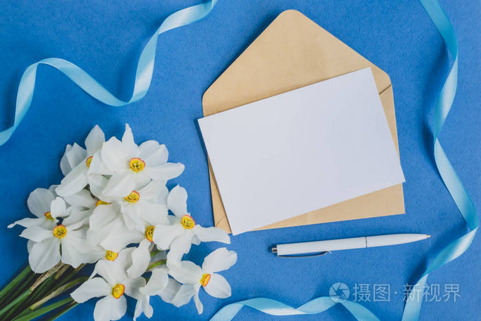 白色贺卡和带有白色水仙花和蓝色背景的信封