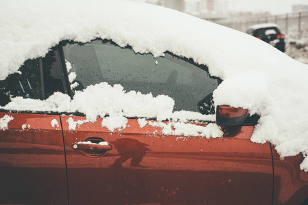 红色汽车的近景覆盖着新鲜蓬松的雪
