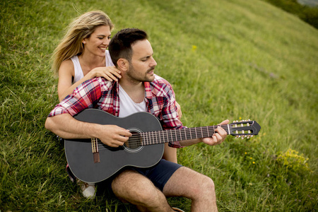 和女友坐在草地上弹吉他