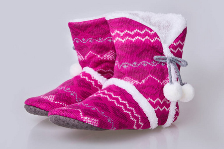 白色背景上的粉红色针织拖鞋。 柔软温暖舒适的家用拖鞋