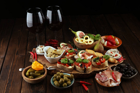 意大利反帕斯蒂葡萄酒小吃一套。 奶酪品种，地中海橄榄，咸菜，火腿，西红柿，洋蓟和酒杯中的葡萄酒。