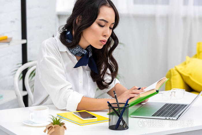 亚洲自由职业者在办公室工作桌上工作手拿钢笔看书