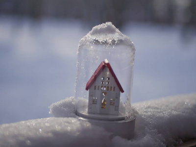 一个小玩具，装饰白色的房子，有一个红色的屋顶，雪上有灯光照明，冬季季节性假日的概念，圣诞节，新年的新家，家庭舒适。